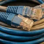 Blue ethernet plugs resting on coiled blue and grey network cables with a braided copper sleeve