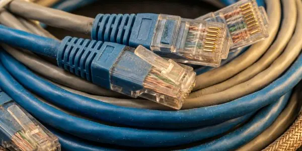 Blue ethernet plugs resting on coiled blue and grey network cables with a braided copper sleeve