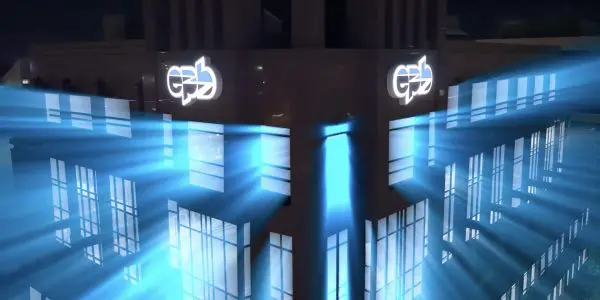The building is illuminated with bright blue light, showcasing a modern architectural design against a dark night sky.