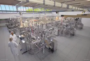 A large, modern laboratory contains complex machinery with silver and white components, set within a bright, spacious room.