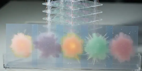 A layered acrylic structure holds glowing, colourful spherical forms resembling neural network nodes, set against a dark background.