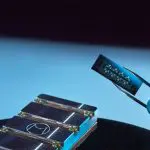 Alice and Bob Helium cat-qubit chip held in tweezers above its sample mounts