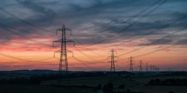 Transmission pylons receding across fields at dusk