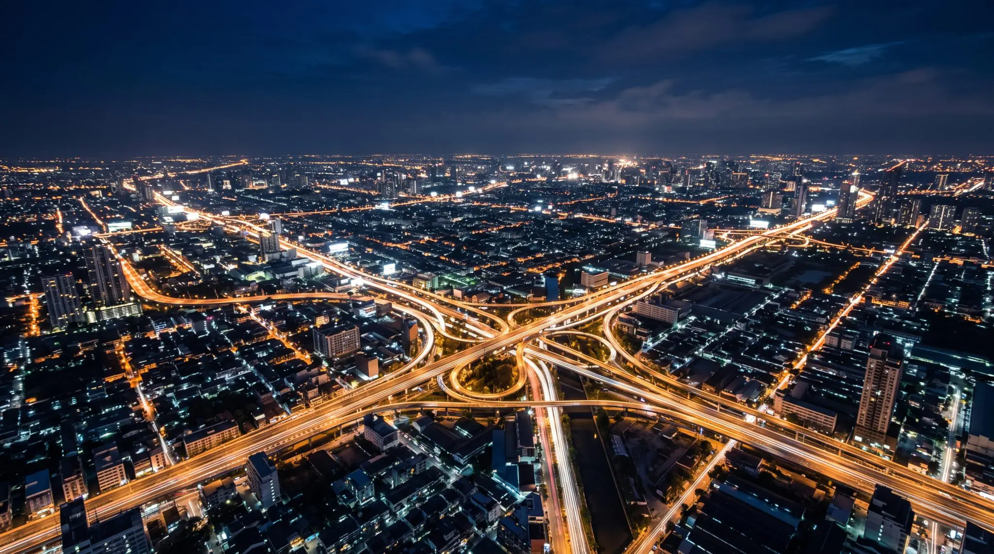 Aerial night view of a sprawling city with glowing highway interchanges