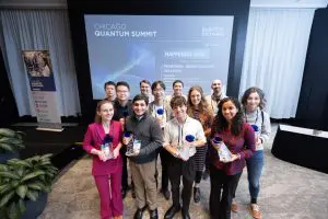 A group of young people stand together holding awards in a modern conference room with a large screen.