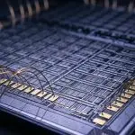 A close-up of a complex microchip with gold connecting wires, set against a dark background with blue highlights.