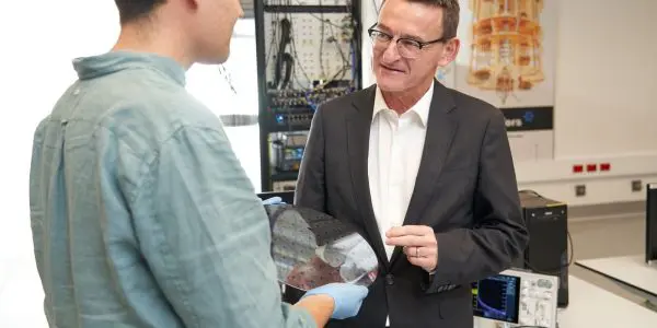 A 300mm silicon wafer of Diraq spin-qubit devices held in the laboratory, with measurement racks behind