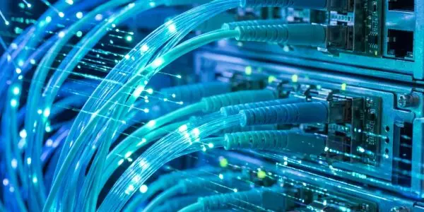 Bundles of glowing cyan fibre optic cables plugged into a network switch