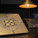 Golden circuit boards with intricate patterns are lit by a warm lamp on a dark surface, creating a futuristic scene.