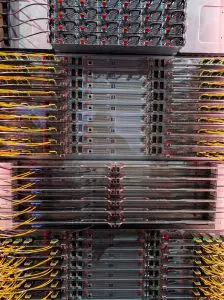 A server rack filled with densely packed computing hardware dominates the frame, illuminated by cool, artificial light