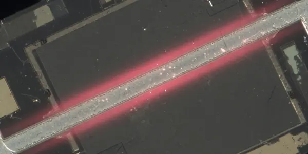 A microchip with a central, glowing red structure is visible under a microscope, set against a dark background.