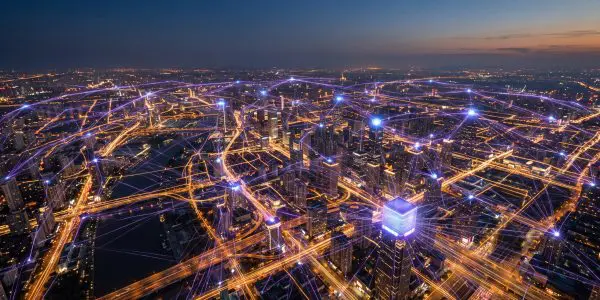 aerial dusk view of a city laced with glowing purple network links between rooftops