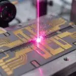 A magenta laser striking a trapped-ion chip