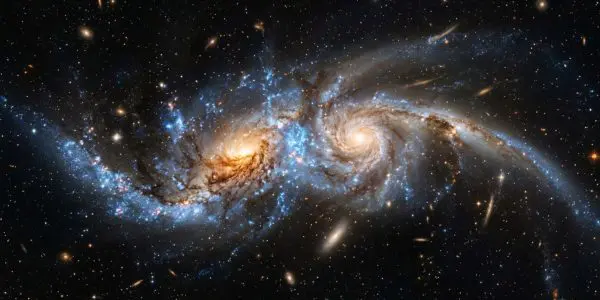 This stunning image showcases a spiral galaxy interacting with another, set against a backdrop of countless stars and cosmic dust.