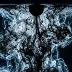 Dark blue water swirls with flowing black ink, creating an ethereal, abstract pattern with shimmering highlights