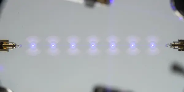A microchip with a series of glowing blue light sources arranged in a line, set against a dark background.