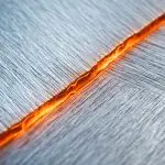 A glowing orange boundary between two brushed metal domains