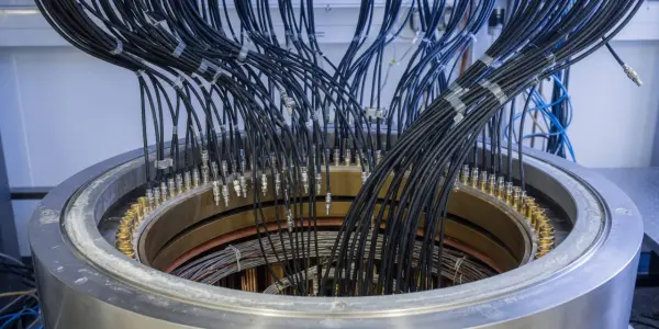A complex metallic apparatus with numerous cables connected, set in a laboratory with cool blue and silver tones.