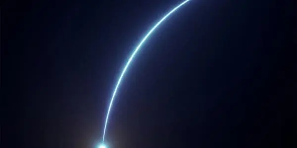 A bright blue point of light at lower left with a thin curved arc of light sweeping upward and to the right across darkness.