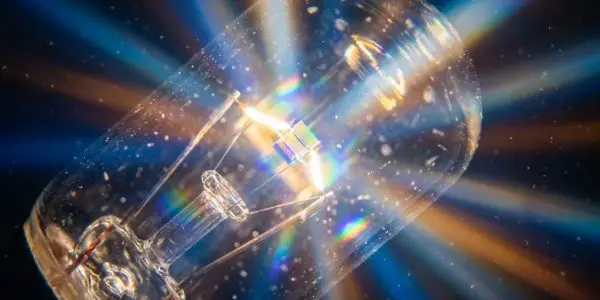 Clear halogen bulb with a glowing filament surrounded by rainbow light rays