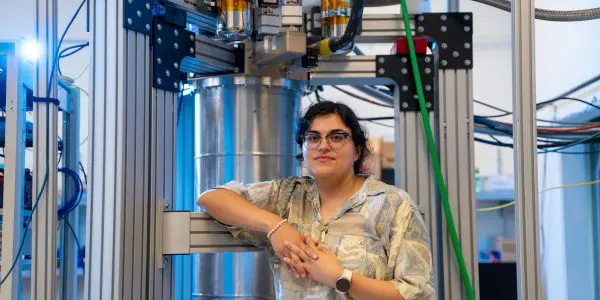 Faith Reyes stands in front of a large device in the lab
