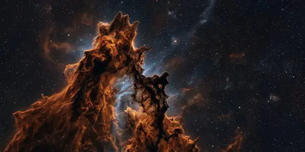 Towering orange dust pillars in a nebula, backlit by blue gas against a starfield