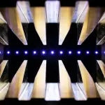 A symmetrical arrangement of golden, triangular prisms converges on a bright blue light source in darkness