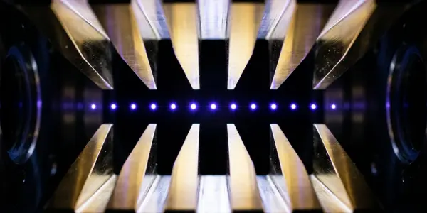 A symmetrical arrangement of golden, triangular prisms converges on a bright blue light source in darkness