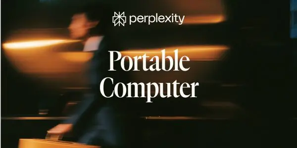 A blurred figure is working on a portable computer at a dark table with warm orange and white lighting.