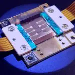 This close-up shot shows a complex electronic component on a blue surface, illuminated with a spotlight.