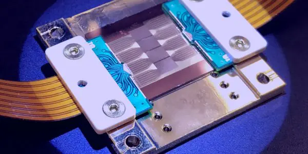 This close-up shot shows a complex electronic component on a blue surface, illuminated with a spotlight.