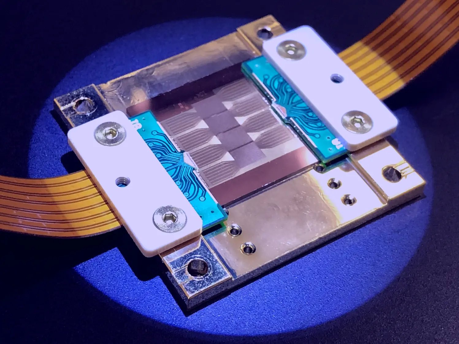 This close-up shot shows a complex electronic component on a blue surface, illuminated with a spotlight.