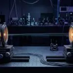 Two facing optical detector mounts linked by thin light beams across a dark optical table