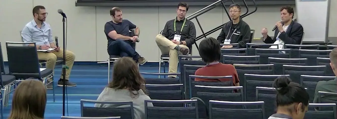 Five people seated on a conference stage for a panel on automated qubit calibration, with an audience in front