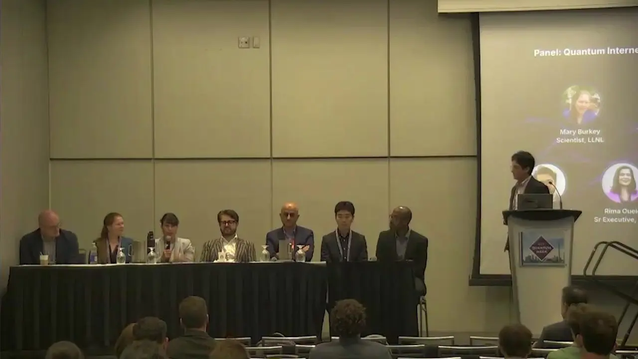 Panel of eight speakers at a table on quantum network business.