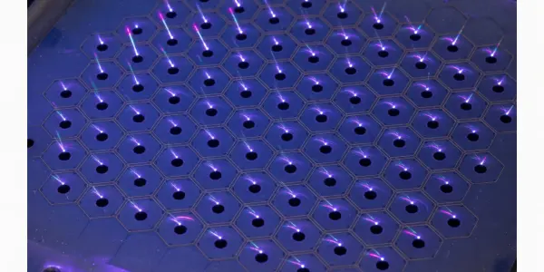 A hexagonal array of purple laser beams shine upwards from a dark metallic surface, creating a futuristic, high-tech aesthetic.
