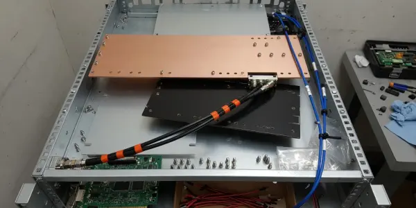 An open rack chassis of quantum control electronics with a copper plate, circuit boards and cables