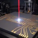 A red laser striking a gold ion-trap chip