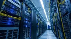 This image shows a long corridor filled with rows of servers, illuminated with blue and white lighting.