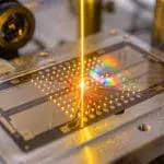 An amber beam on an ion trap splitting into diffracted colours