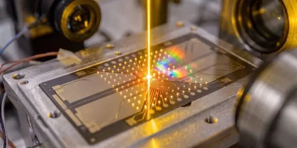 An amber beam on an ion trap splitting into diffracted colours