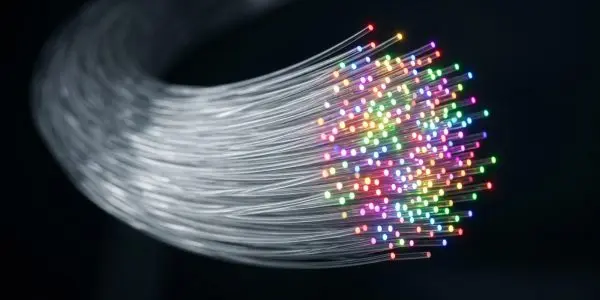 A swirling bundle of optical fibres glows with vibrant, multicoloured light against a dark, blurred background.