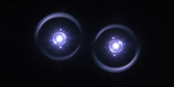 Two bright, circular light sources glow against a black background, radiating white and pale blue light in a dark, futuristic setting.