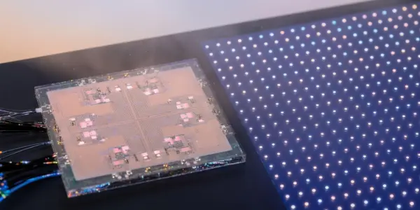 A complex circuit board and a grid of illuminated points are displayed in a dark laboratory setting, with blue and pink hues.