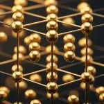 A golden, three-dimensional lattice structure glows against a dark background, suggesting interconnectedness and complex systems.