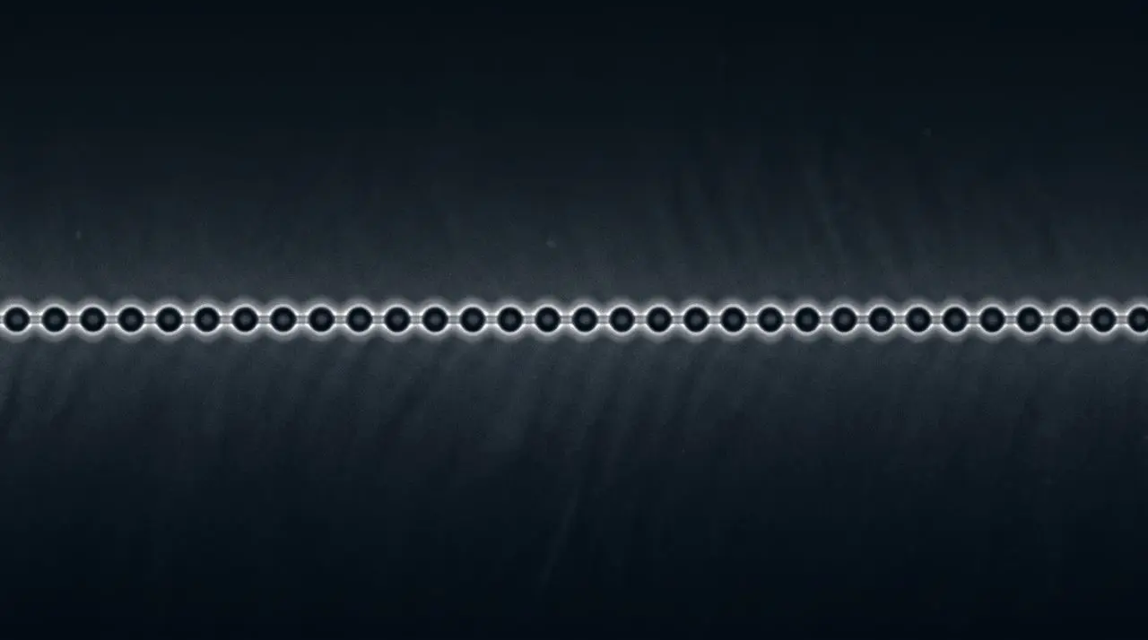 A horizontal row of small, grey beads is displayed against a dark blue background with subtle texture.