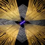 A symmetrical composition of circuit boards and golden traces converges on a central blue LED cross, set against black.