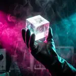 A gloved hand holding a clear crystal cube