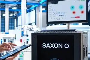 A dark-coloured quantum computer is shown in a bright, industrial setting with a monitor displaying data graphs.