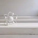 A white atomic model sits on a plinth in a bright, minimalist room with a window, creating a stark, clean aesthetic.